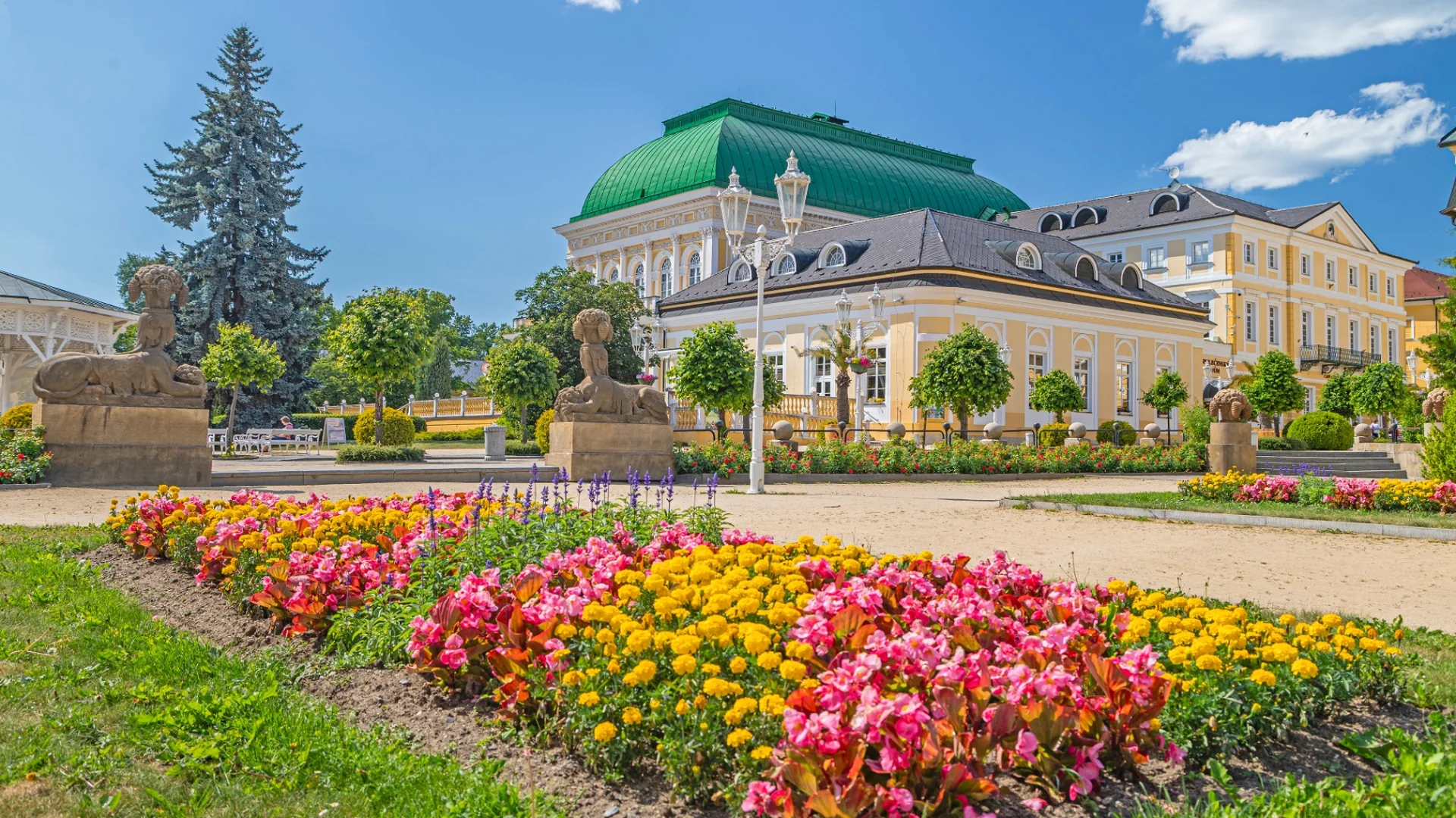 Park se sfingami a květinovými záhony před Společenským Domem